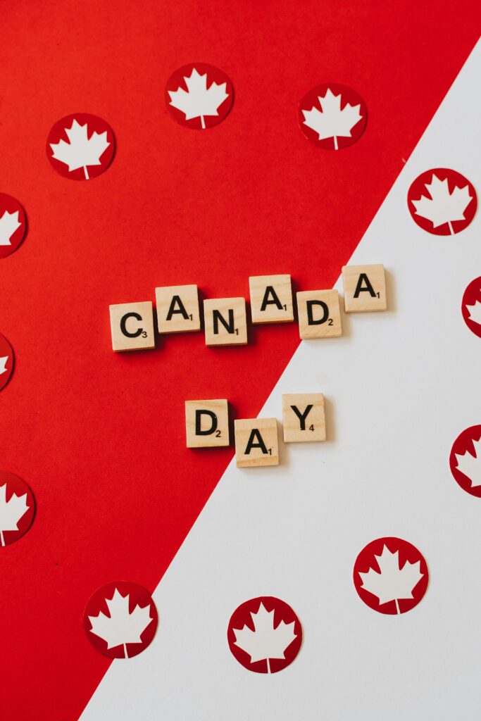 Scrabble letters spelling 'Canada Day' on red and white background with maple leaf symbols.
